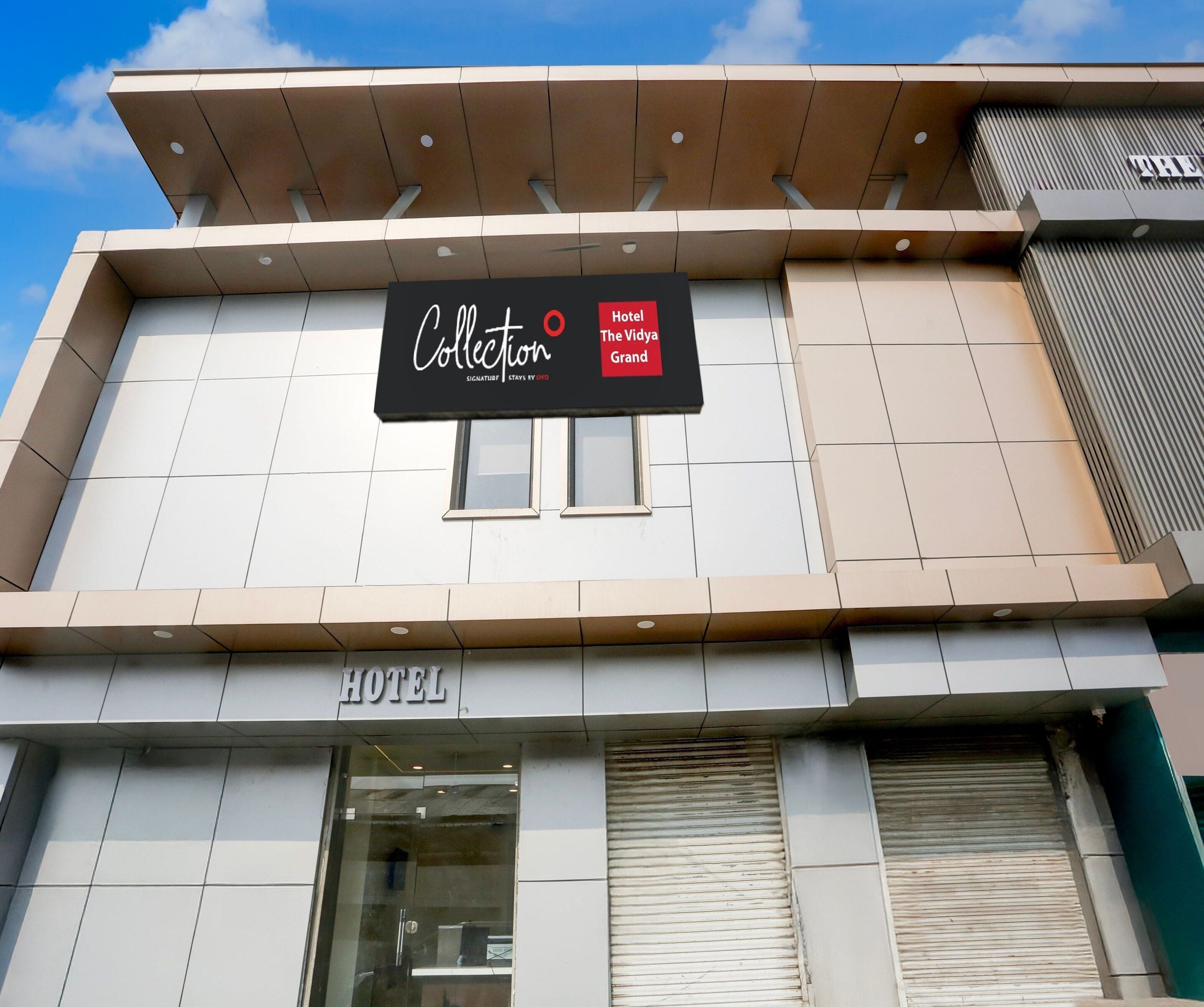 A hotel sign with the name 'Hotel The Vidya Grand' and a sign for 'Collection' above it.