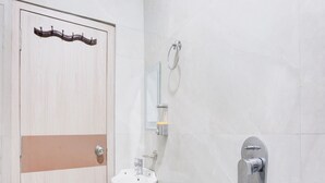 Ein Badezimmer mit Holztür, Waschbecken, Spiegel und Dusche.