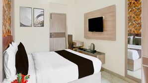 Ein Hotelzimmer mit Bett, Schreibtisch, Fernseher und Bildern an den Wänden.