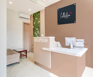 A reception area with a reception desk, a sign reading 'RECEPTION', and a wall-mounted sign above the desk. - Deluxe Vidya Grand (Kichha)