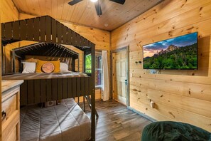 L'intérieur d'une cabine est aménagé avec un lit superposé, un téléviseur fixé au mur et une fenêtre donnant sur l'extérieur.