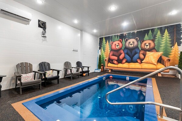 Un espace piscine agrémenté d’une fresque représentant des ours, des chaises et un canapé.