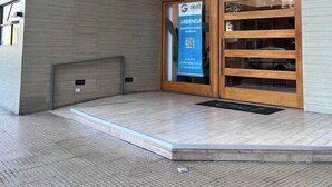 A modern building entrance with a glass door, a blue rental sign, and a number '050' on the wall. - 2BR/2B Suite, A/C and heating, Parking (Estación Central)