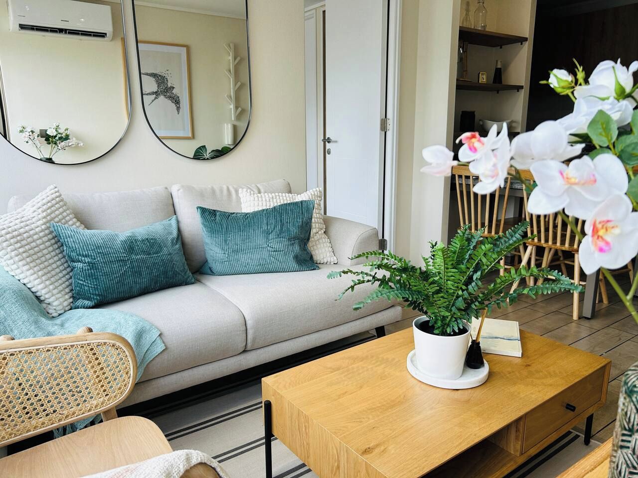 A living room with a sofa, a coffee table with a plant, and a mirror on the wall.