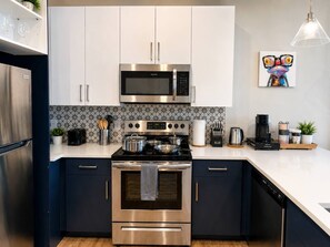 Een moderne keuken met roestvrijstalen apparatuur, witte kastjes en een decoratieve spatwand.