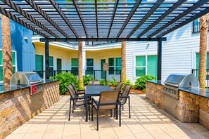 Eine Terrasse im Freien mit Grill, Tisch und Stühlen.