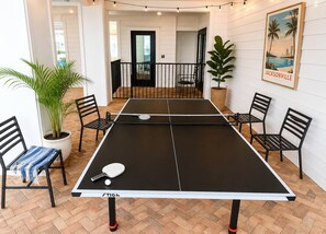 A ping pong table with chairs, a potted plant, and a framed picture on the wall. - Modern King Bed Balcony Pool View Gym EV San Marco (Jacksonville)