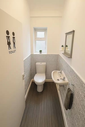 Ein kleines, modernes Badezimmer mit Toilette, Waschbecken und Fenster.