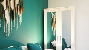 A bedroom with teal walls, a white wardrobe, and a mirror reflecting the room. - Room-double Room With Work Station Free (Wolverhampton)