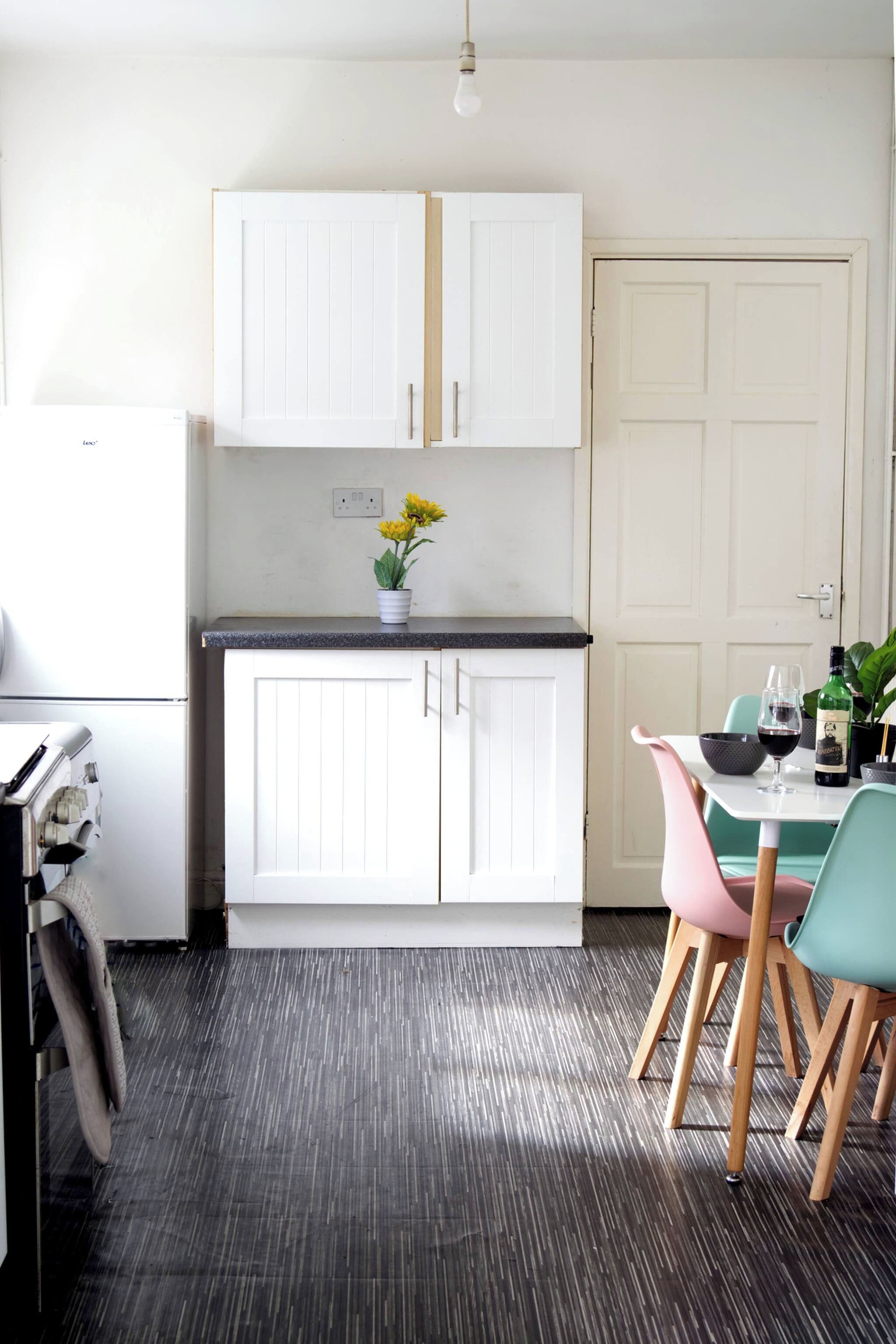 A kitchen with white cabinets, a black countertop, and a dining area with a table and chairs.