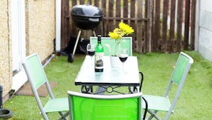 A small patio with a table and chairs, a grill, and a wooden fence in the background. - Room-double Room With Work Station Free (Wolverhampton)