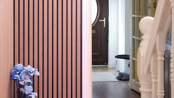 Un mur recouvert de panneaux de bois, un escalier et une porte donnant sur une pièce dotée d’une fenêtre circulaire.