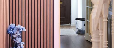 Pared de paneles de madera, una escalera y una puerta que da a una habitación con un ventanal circular.