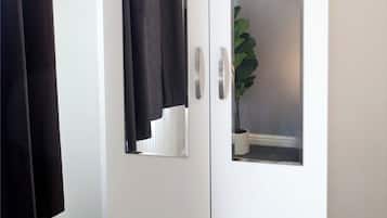 A white wardrobe with a mirrored door and a plant inside.