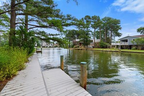 A wooden dock extending into a calm water body with a clear sky above. - Villa Annick | Affordable Waterfront Retreat in Oyster Bay I (Chincoteague Island)