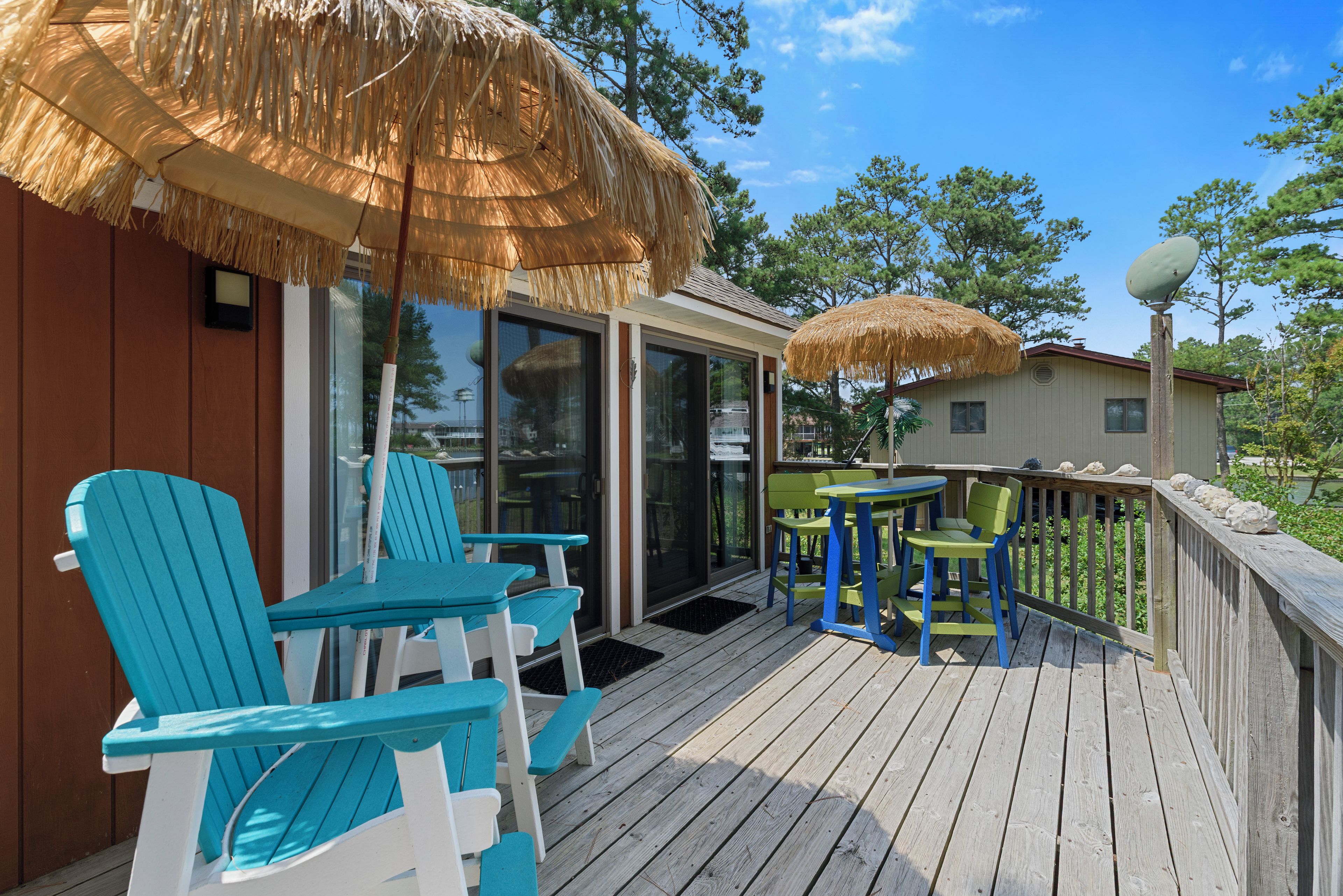 A deck with outdoor seating, including chairs and tables, and a covered area with a thatched roof.
