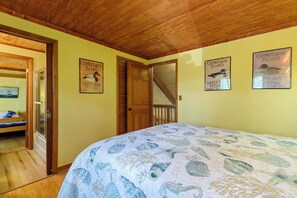 A room with a bed, wooden ceiling, and two posters on the wall. - Villa Annick | Affordable Waterfront Retreat in Oyster Bay I (Chincoteague Island)
