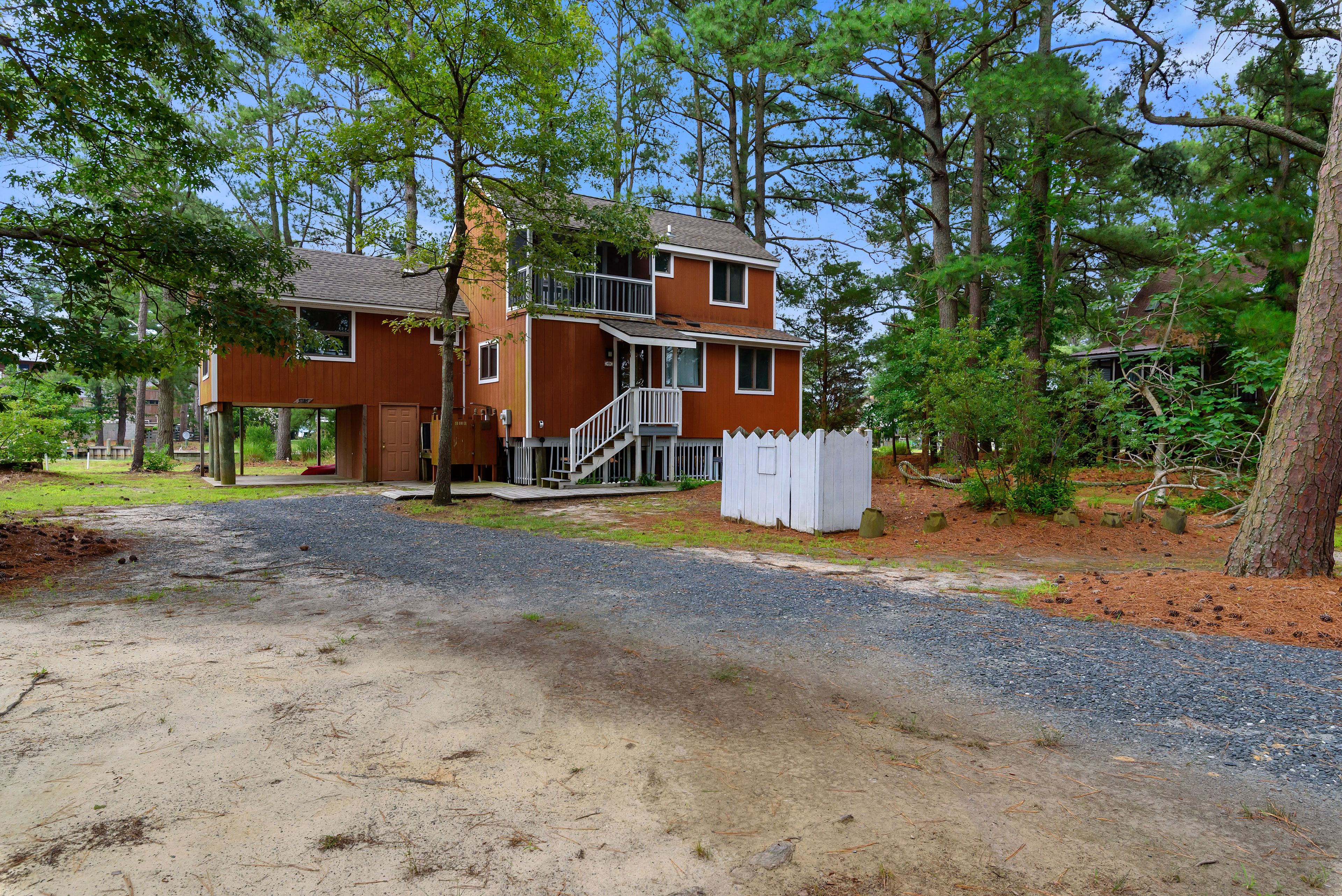 A two-story wooden house with a front porch and a white picket fence.