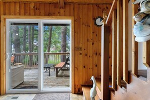 A wooden cabin interior with a sliding glass door leading to an outdoor deck. - Villa Annick | Affordable Waterfront Retreat in Oyster Bay I (Chincoteague Island)