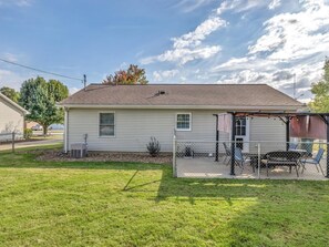 Une maison de plain-pied avec un patio couvert, une pelouse et un arbre en arrière-plan.