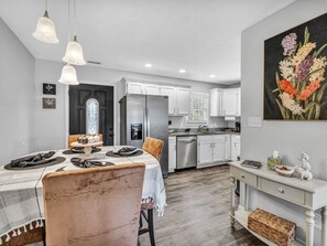 Une cuisine moderne avec des meubles blancs, un réfrigérateur encastré et un coin repas comprenant une table et des chaises en marbre.
