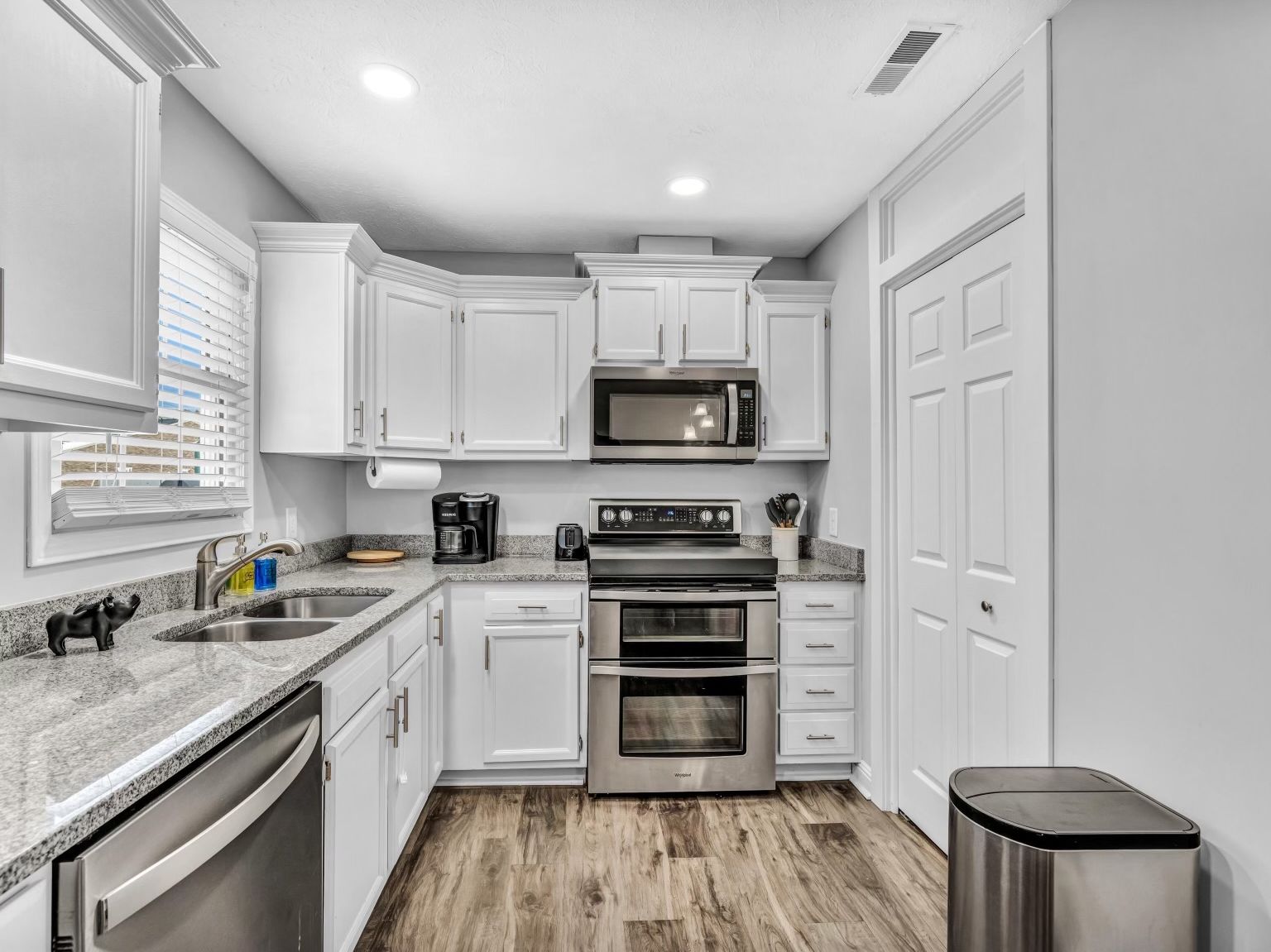 A compact kitchen with white cabinetry, a stainless steel range, a microwave, and a dishwasher.