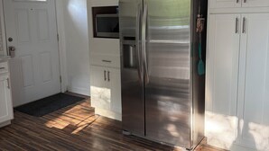 Une cuisine avec des armoires blanches, un réfrigérateur en acier inoxydable et un four à micro-ondes.