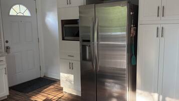 A kitchen with white cabinets, a stainless steel refrigerator, and a microwave.