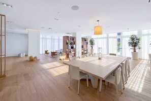 A spacious, well-lit room with a large dining table, multiple chairs, and a bookshelf. - Tiffany Celeste - Walk to Beach, Water Views, Rooftop Pool (Fort Lauderdale)