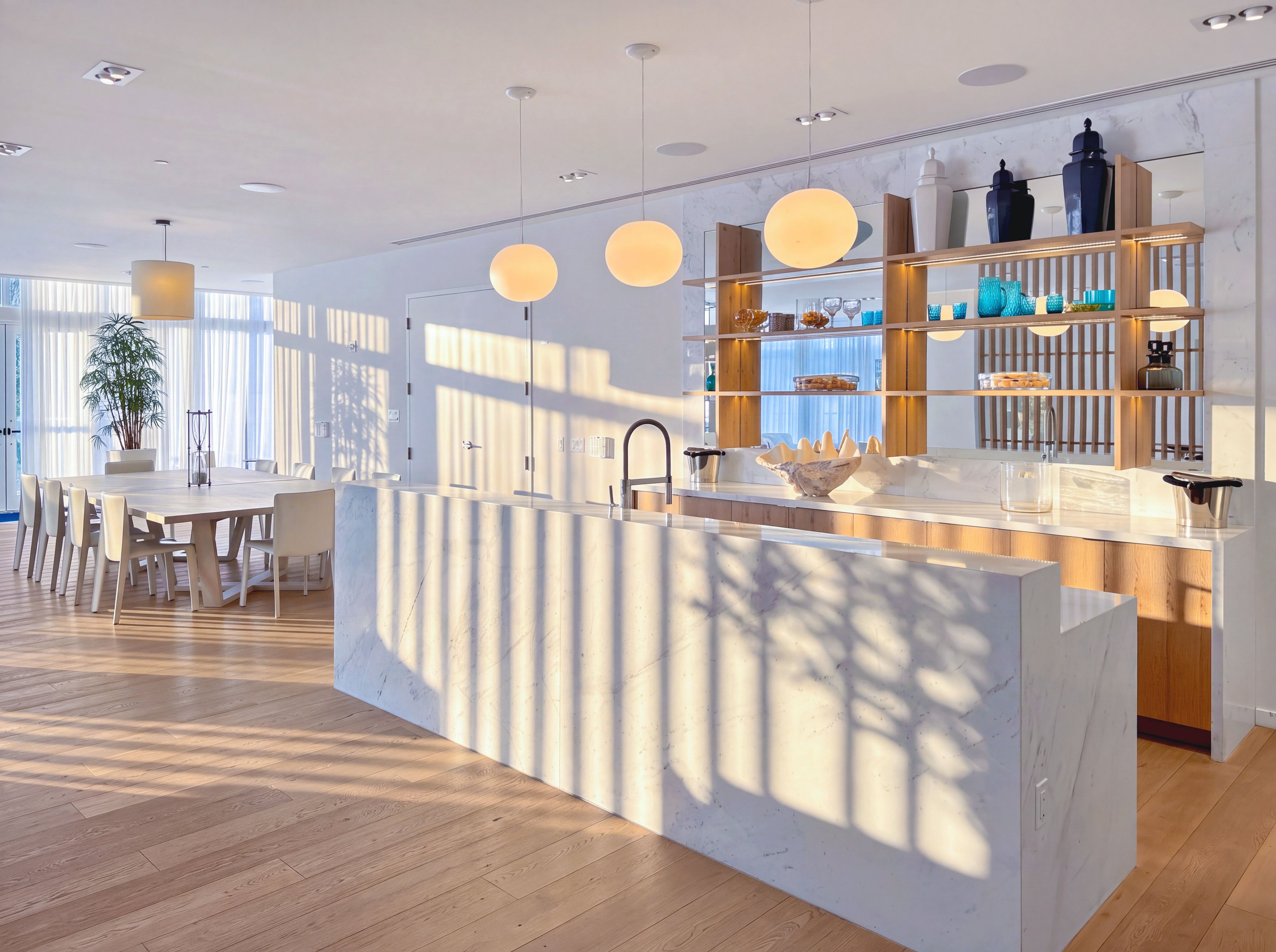 A modern kitchen with a central island, pendant lighting, and a view of the dining area.