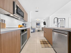 A modern kitchen with built-in appliances, a flat-screen TV, and a central island. - Tiffany Celeste - Walk to Beach, Water Views, Rooftop Pool (Fort Lauderdale)