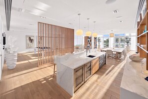 A modern kitchen with a central island, wooden flooring, and pendant lighting. - Tiffany Celeste - Walk to Beach, Water Views, Rooftop Pool (Fort Lauderdale)
