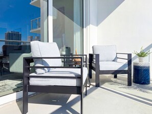 A modern outdoor seating area with two chairs and a table, a potted plant, and a view of the cityscape. - Tiffany Celeste - Walk to Beach, Water Views, Rooftop Pool (Fort Lauderdale)