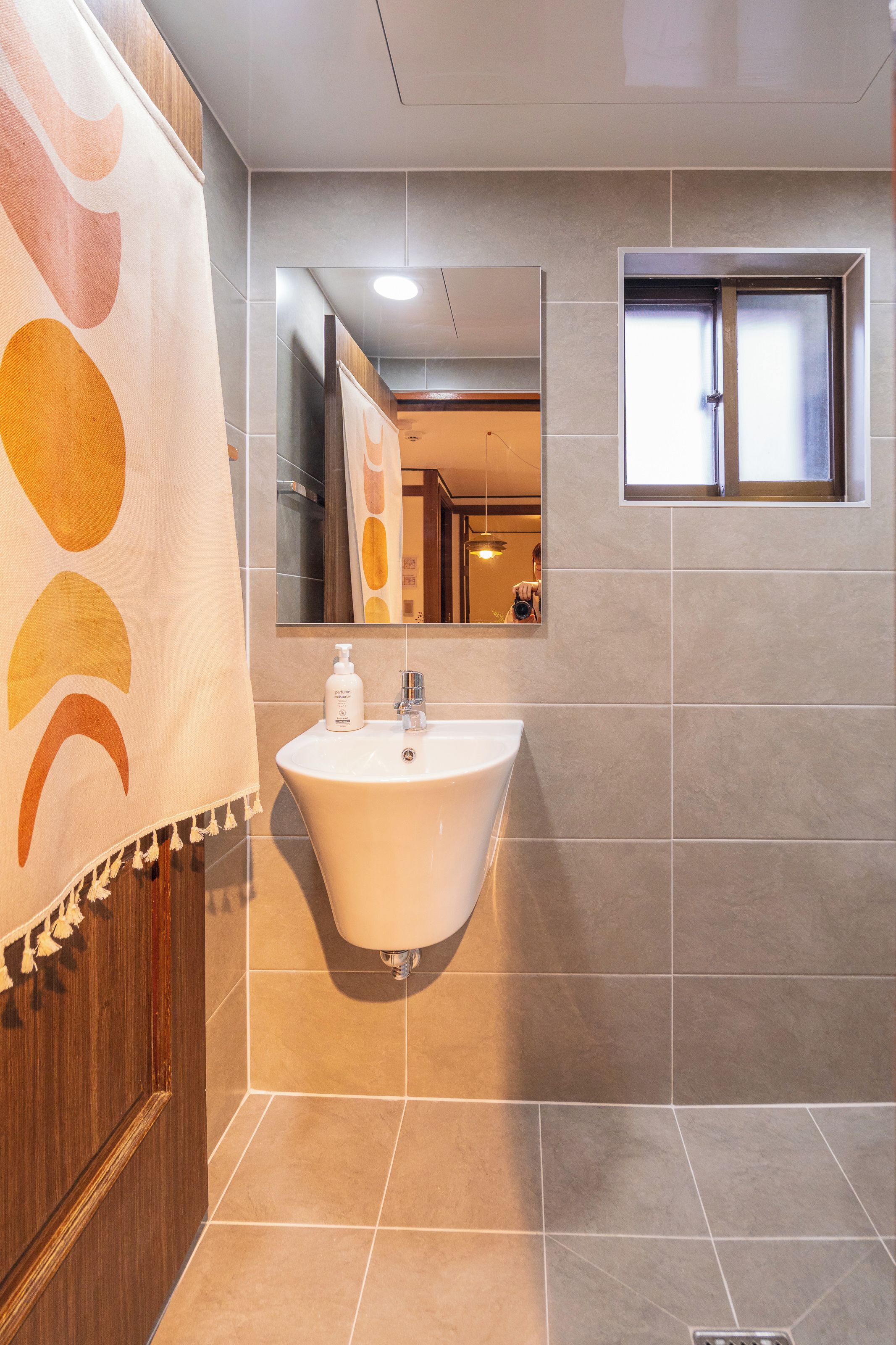 A bathroom with a freestanding sink, a mirror, and a window.