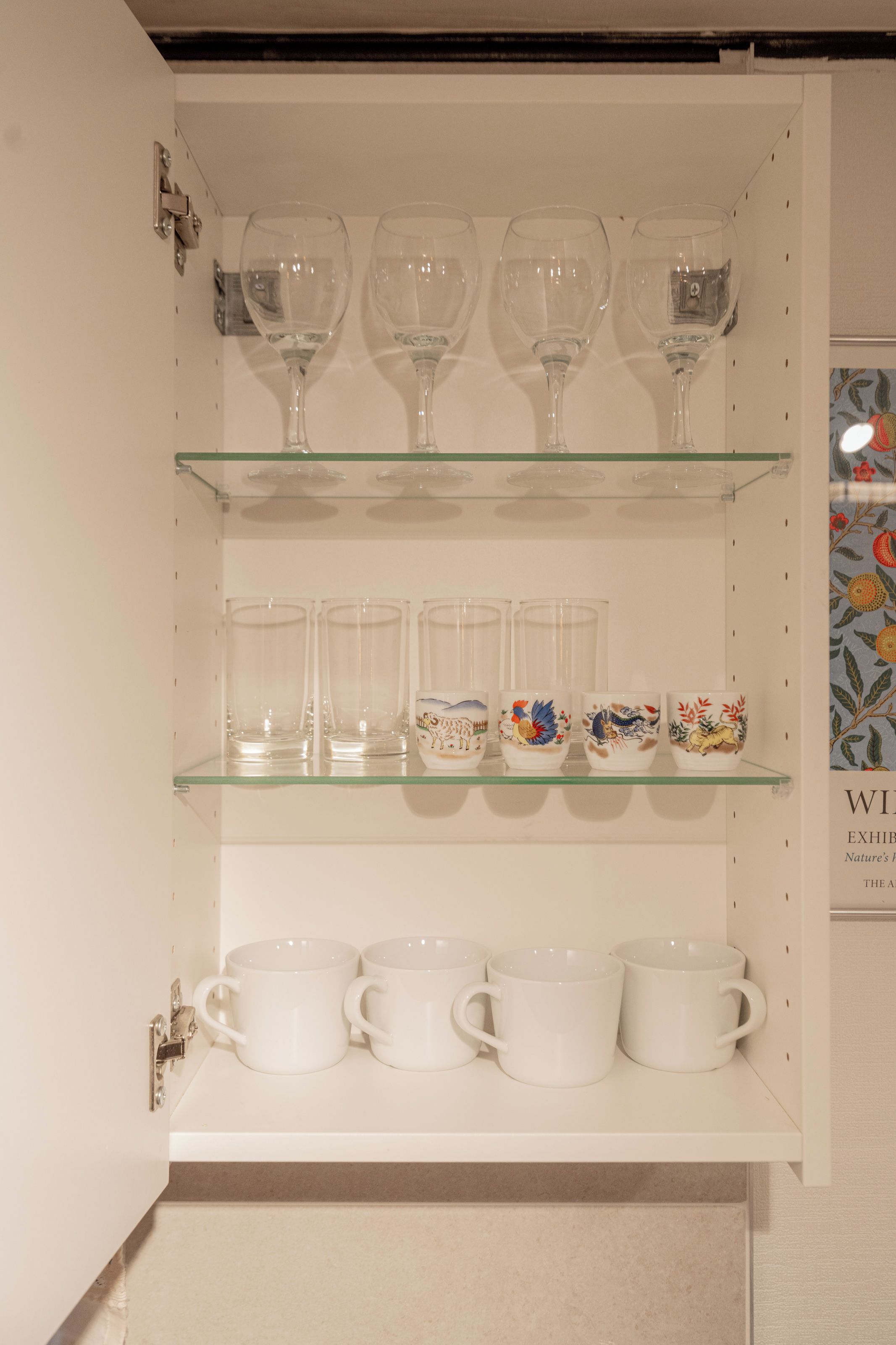 Una vitrina con repisas que contiene varios vasos y tazas de cerámica.