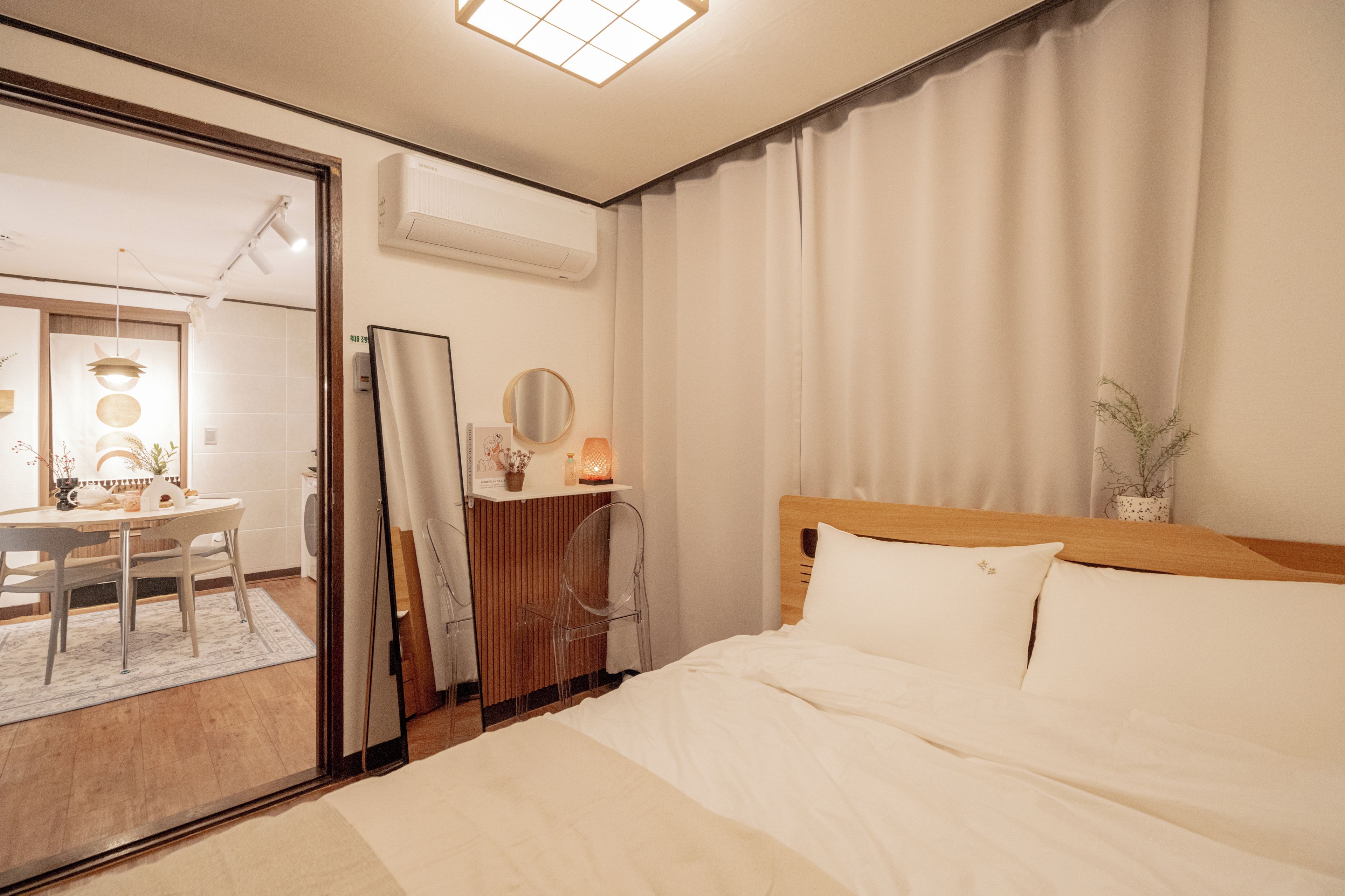 Una habitación de hotel con cama, escritorio, espejo y ventana con cortinas.