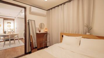 Una habitación de hotel con cama, escritorio, espejo y ventana con cortinas.