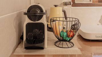 Una kitchenette con cafetera, una cesta de cápsulas de café y un microondas.