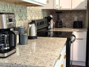 Eine Küche mit Granit Arbeitsplatte, einer Kaffeemaschine, einem Wasserkocher, einem Toaster und einem Mixer.