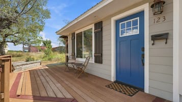 A house with a blue door, a porch with wooden flooring, and a number 123 on the wall.