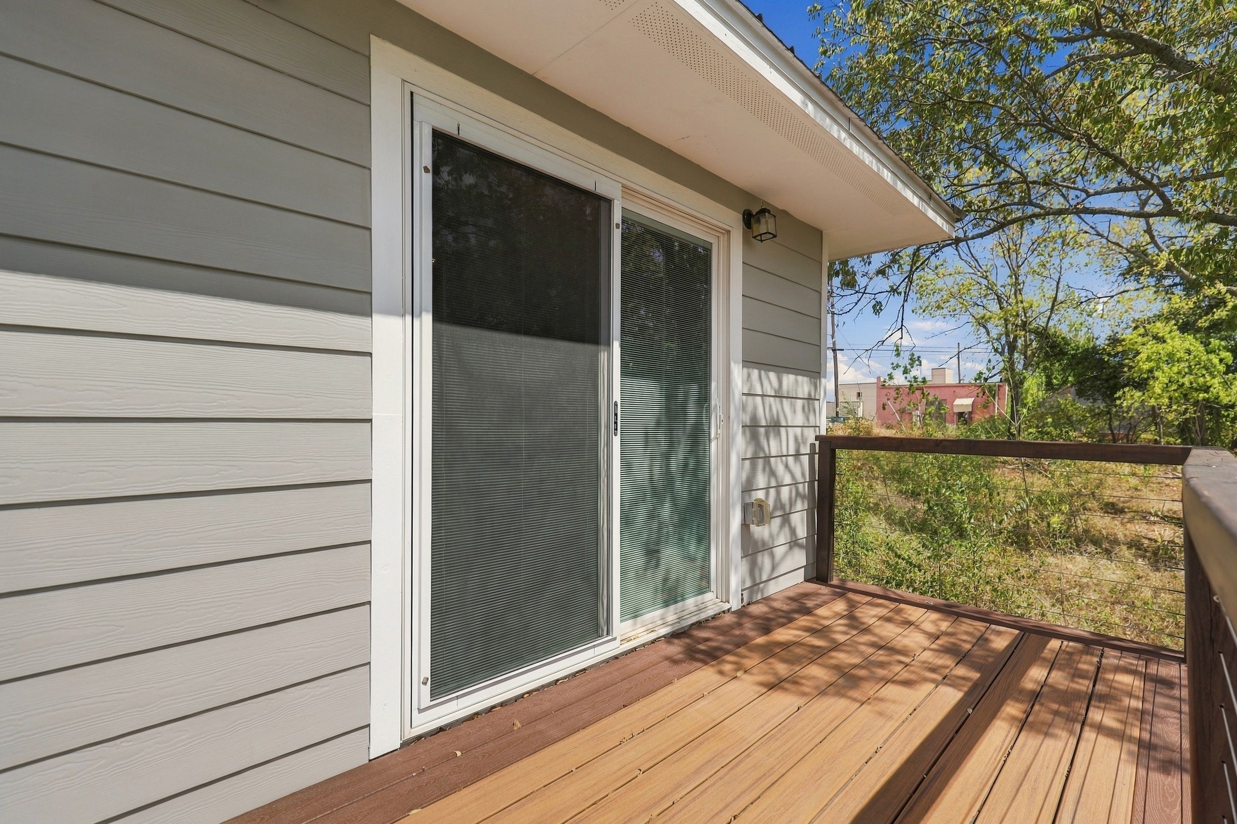 A wooden deck with a sliding glass door leading to a covered porch.