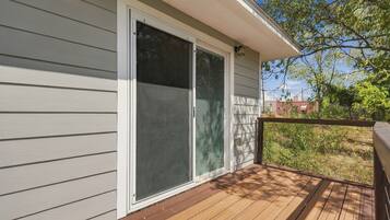 A wooden deck with a sliding glass door leading to a covered porch.