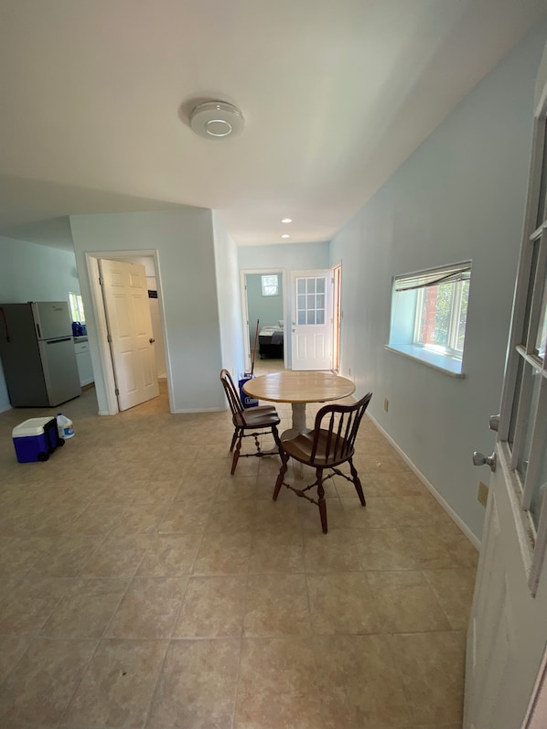 A kitchen with a dining table and chairs, a refrigerator, and a water cooler.