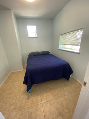 A bedroom with a bed, two windows, and a door.