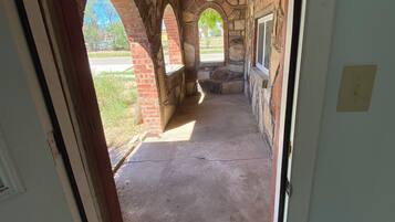 Un pasillo interior con arcos de piedra, suelo de hormigón y vistas al exterior.