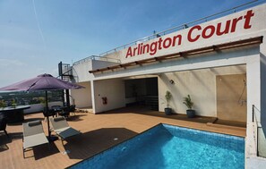 A rooftop pool area with a sign reading 'Arlington Court,' outdoor seating, and a view of the city. - Fantastic  1-bedroom apartment Arlington Court East Legon Accra (Accra)