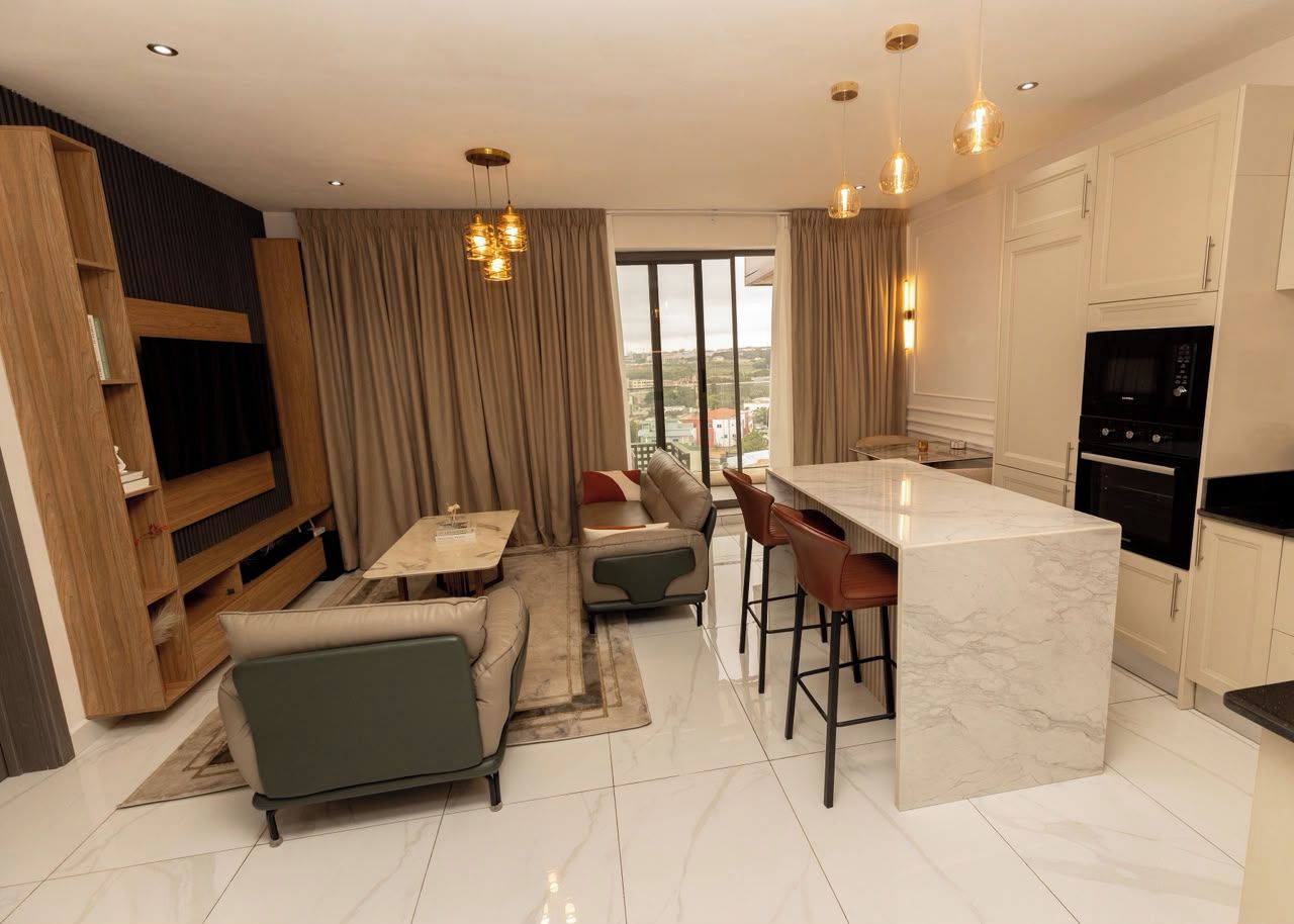 A modern living room with a sofa, a dining area, and a kitchen with a marble island.