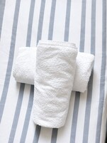 Un asciugamano bianco piegato su una coperta a righe.