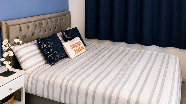 A bedroom with a tufted headboard, striped bedding, a chandelier, a framed picture, and dark curtains. - Room-cozy En-suite Room Netflix, Fast Wi (Wolverhampton)