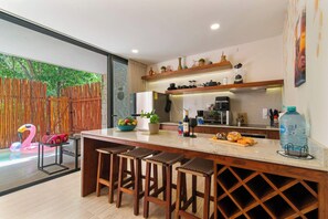Cozinha moderna com ilha central, banquetas e vista para uma piscina.